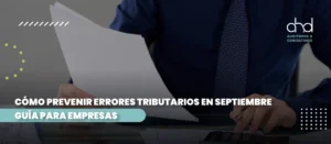 Empresario revisando documentos y usando calculadora, representando la prevención de errores tributarios en septiembre.