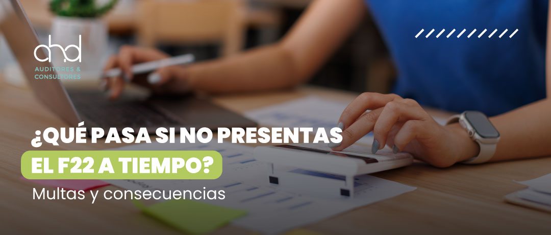 Persona calculando impuestos con laptop y calculadora sobre escritorio – AHD Auditores